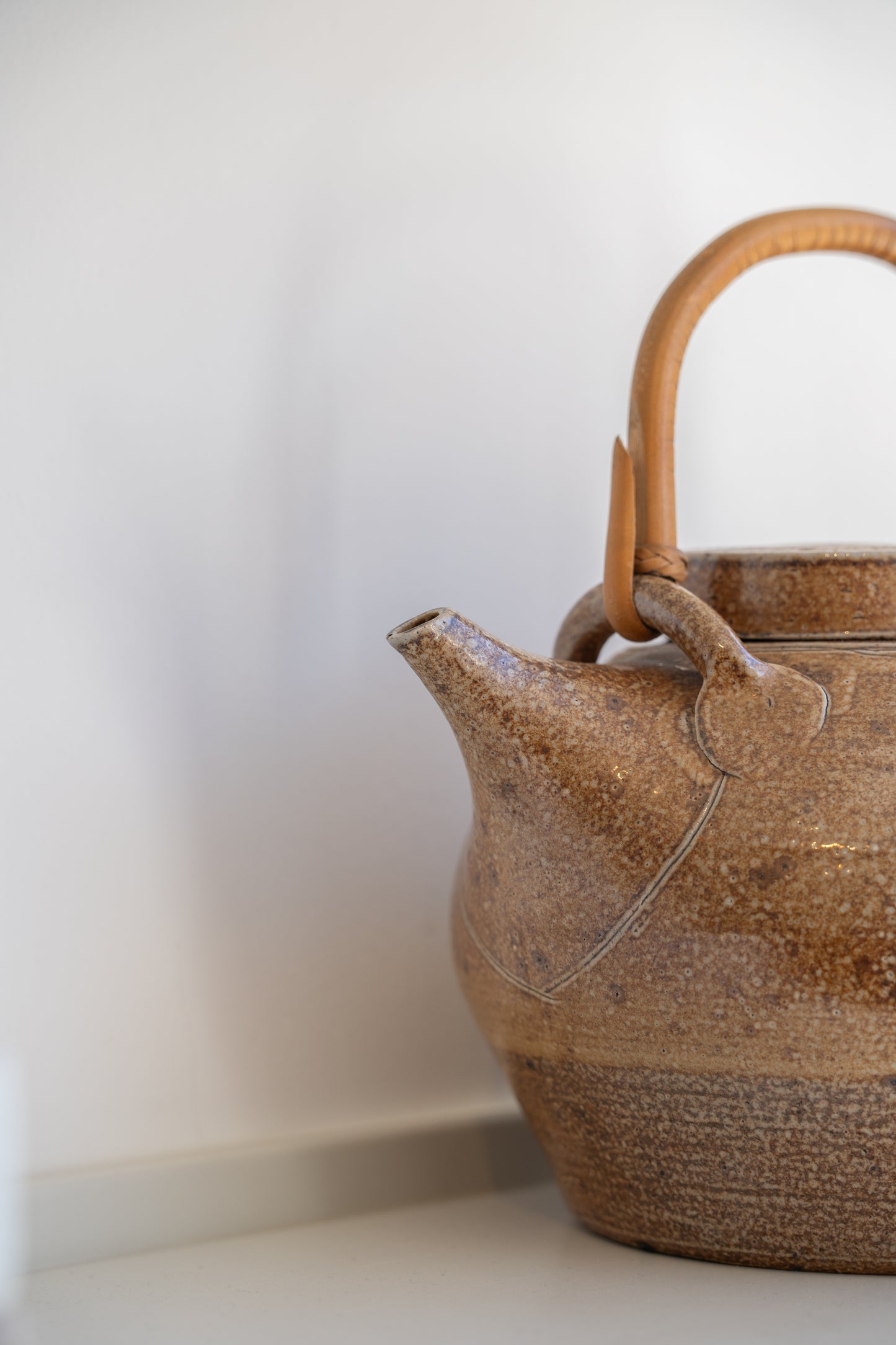 A salt glazed studio pottery teapot and cover with bamboo swing handle by  Sarah Walton (UK) 1970s